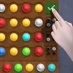 Bàn trò chơi với các viên bi màu sắc khác nhau và bàn tay đang nhấn vào một nút có dấu kiểm