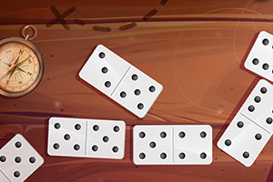 Các quân cờ domino màu trắng nằm trên bề mặt gỗ nâu, bên cạnh một chiếc la bàn cổ điển