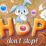 Một chú thỏ xanh đáng yêu ngồi trên chữ HOP được viền màu cam, xung quanh là các viên đá quý nhiều màu sắc trong khung cảnh rừng thu lá vàng