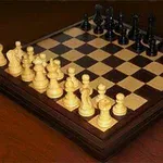 Bàn cờ vua với các quân trắng và đen được sắp xếp ở vị trí bắt đầu trên bàn gỗ