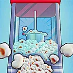 Máy làm bỏng ngô đang hoạt động với nhiều hạt bỏng ngô màu trắng rơi ra ngoài
