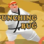 Người đàn ông mặc trang phục võ thuật trắng với băng đầu đỏ đứng trong khung cảnh sa mạc bên cạnh dòng chữ PUNCHING BUG