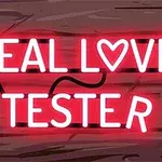 Dòng chữ REAL LOVE TESTER bằng đèn neon màu đỏ trên nền gỗ với hình trái tim thay cho chữ O