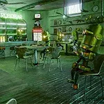 Bên trong quán bar với vài con robot ngồi, ánh sáng xanh lục, bảng hiệu Le Robobar