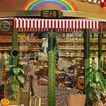 Quán cà phê với cửa kính lớn, cây xanh và mái hiên sọc đỏ trắng