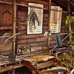 Ngôi nhà gỗ nhỏ với cửa sổ chớp trắng và các vật dụng treo bên ngoài trên hàng rào