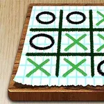 Bàn gỗ với giấy kẻ ô chứa các dấu X và O vẽ tay